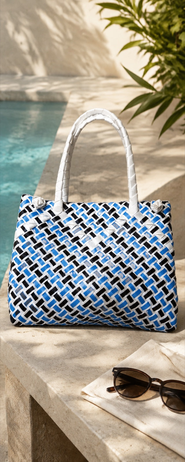 Blue, white, and black recycled-polypropylene ISA BAYONG bag beside a pool